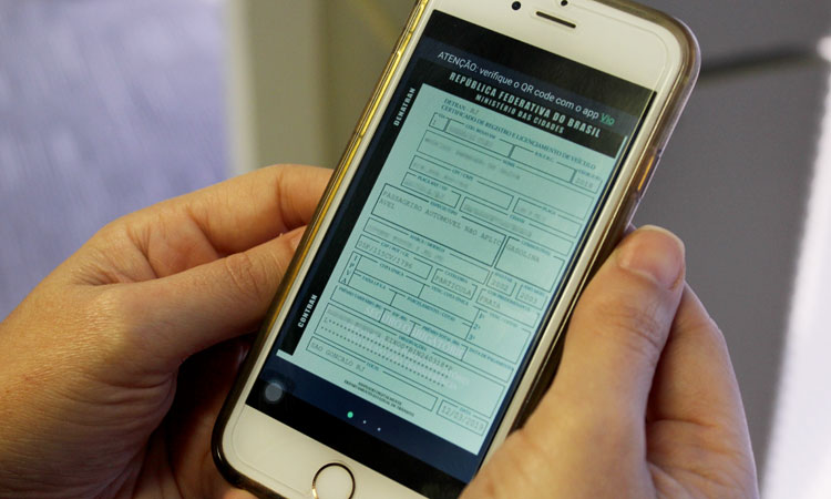 (Foto: divulgação) Mãos de um homem segurando um smartphone com a imagem do CRLV Digital na tela