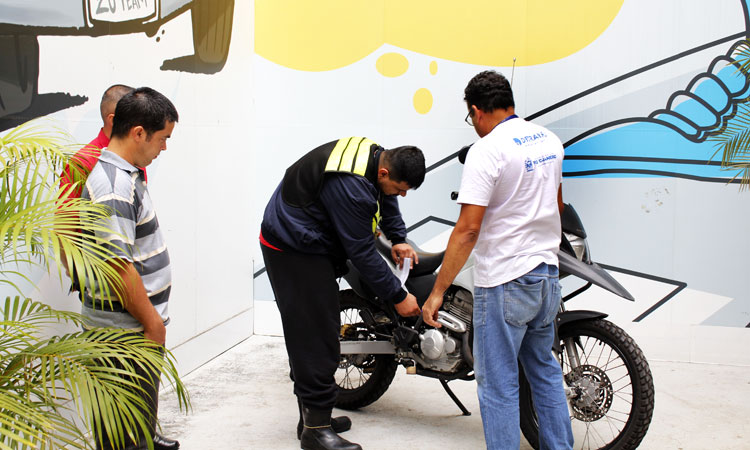 Um instrutor demonstrando a mecânica da moto para três alunos