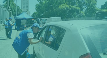 Agente do Detran dá orientaçõesa um motorista dentro do seu automóvel.